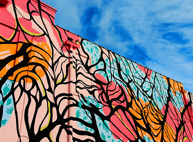 Mural in different colours showing trees on a blue sky background