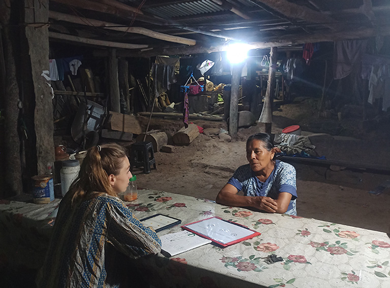 Eine Kleinbäuerin in Peru wird von einer Forscherin in ihrem Haus interviewt