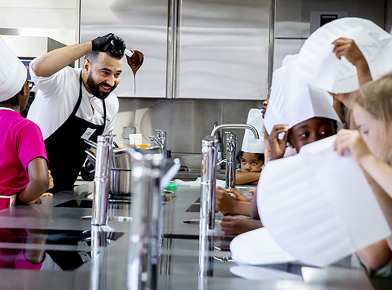 Kinder lernen in den Räumlichkeiten von ma-terre in Genf gemeinsam mit Erwachsenen kochen