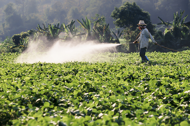 A farmer applies pesticides to soy crops
