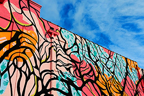 Mural in different colours showing trees on a blue sky background